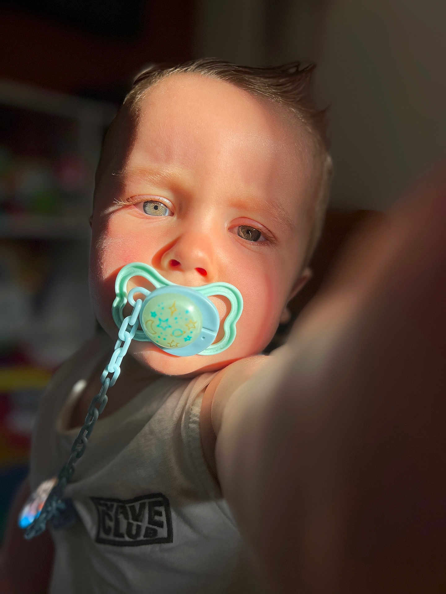 Augustin participe au concours pour gagner de l'argent avec cette photo : baby, blue_eyes, blurred_background, chain, child, closeup, cute, expression, face, heterochromia, indoor, infant, light, pacifier, person, portrait, selfie, shadow, skin, tank_top