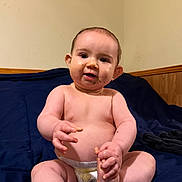 Jameson joined the competition — help win amazing prizes! baby, diaper, infant, sitting, bed, blue_bedspread, food_smudges, cute, chubby, hand, foot, skin, face, expression, curious, indoors, wood_paneling, wall, child, young