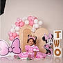 balloons, birthday, blocks, cartoon, celebration, child, costume, cute, decorations, floor, happy, headband, indoor, minnie_mouse, party, pink_dress, portrait, sitting, smile, toddler