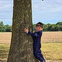 boy, casual, child, daylight, fashion, field, grass, greenery, hugging, nature, outdoor, person, playful, portrait, shoes, sky, smiling, suit, tree, young