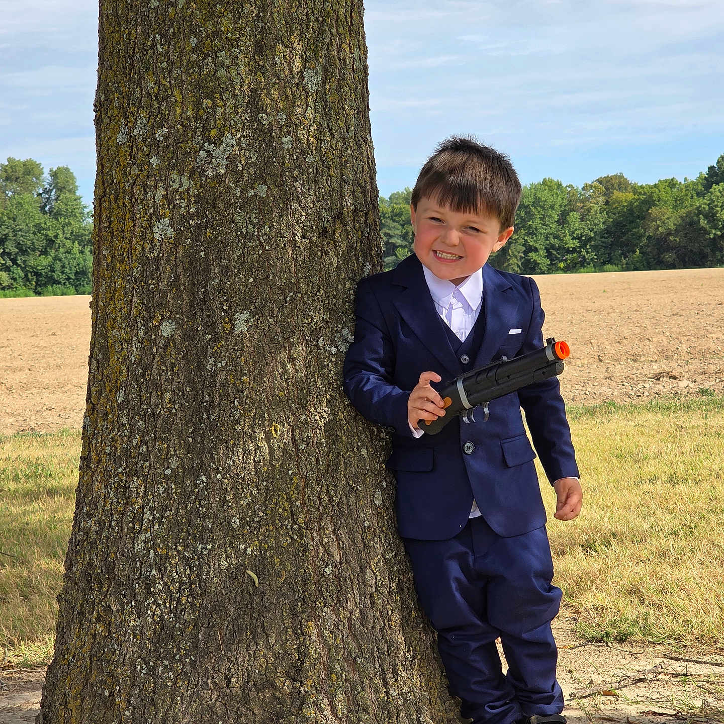 Ryder-Gene joined the competition — help win amazing prizes! boy, casual, child, daylight, fashion, field, fun, grass, happy, leisure, nature, outdoor, person, playful, portrait, smile, suit, toy_gun, tree, young