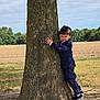 boy, casual, child, clothing, daylight, expression, field, fun, grass, landscape, nature, outdoor, park, person, playing, shoes, suit, tree, tree_trunk, young