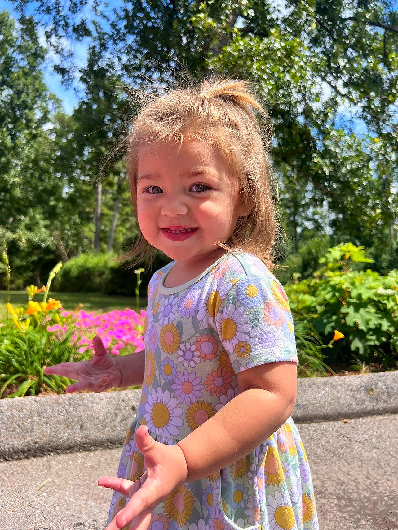 Samantha is registered to the contest to win money with this photo: baby_toddler_clothing, child, dress, eye, facial_expression, flower, fun, grass, happy, iris, leisure, people, people_in_nature, person, pink, plant, sleeve, smile, summer, toddler