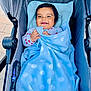 Jack is registered to the contest to win money with this photo: baby, child, stroller, blanket, blue, polka_dot, smile, happy, outdoor, clothing, infant, person, cute, baby_girl, warm, cozy, seat, playful, face, small_hands