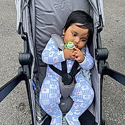Jack is registered to the contest to win money with this photo: baby, child, stroller, pacifier, onesie, blue, gray, outdoor, pavement, infant, seatbelt, cute, young_child, fence, casual, resting, clothing, footwear, sitting, baby_girl