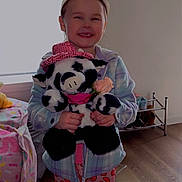 Alaina is registered to the contest to win money with this photo: bed, bedroom, child, clothing, cow, floor, furniture, girl, happy, hat, indoor, pajamas, person, pink, plush_toy, shoes, smiling, toy, warm, window
