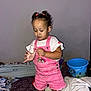 toddler, child, pink_overalls, white_tshirt, barefoot, bed, blankets, bucket, indoor, curly_hair, hair_ties, focused, playing, casual_clothing, young_child, home, floor, furniture, portrait, person