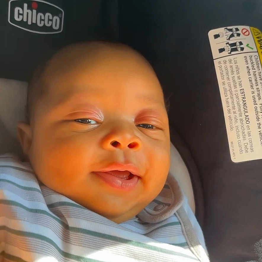 Djuantay is registered to the contest to win money with this photo: baby, car_seat, chicco, child, closeup, clothing, comfort, cute, face, happy, head, indoor, infant, portrait, seat, skin, smiling, striped_blanket, sunlight, young_child