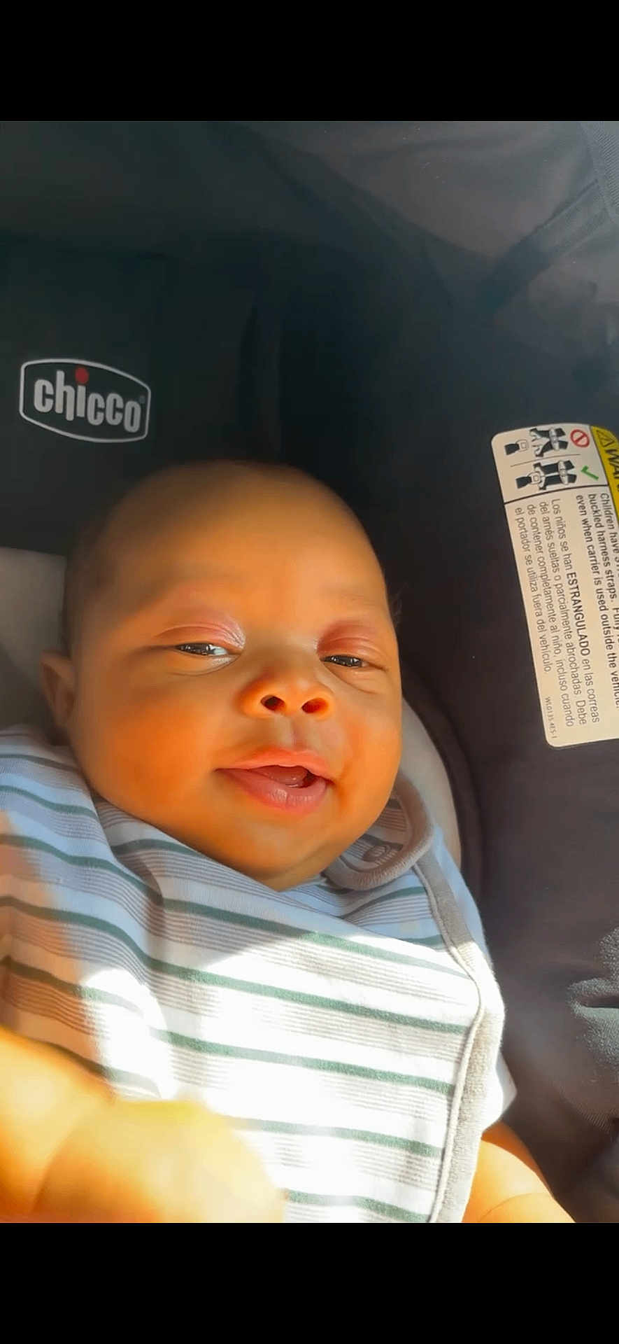 Djuantay is registered to the contest to win money with this photo: baby, car_seat, chicco, child, closeup, clothing, comfort, cute, face, happy, head, indoor, infant, portrait, seat, skin, smiling, striped_blanket, sunlight, young_child