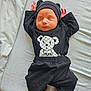 newborn, baby, sleeping, black_clothing, hat, teddy_bear_print, bed, blanket, infant, cute, peaceful, resting, indoors, soft_light, small_hands, small_feet, lying_down, child, portrait, cozy