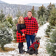Otto joined the competition — help win amazing prizes! boots, cold_weather, couple, dog, evergreen_trees, family, glasses, grass, happy, leash, matching_clothing, nature, outdoor, portrait, pregnant_woman, red_black_checkered, smiling, snow, tree_farm, winter