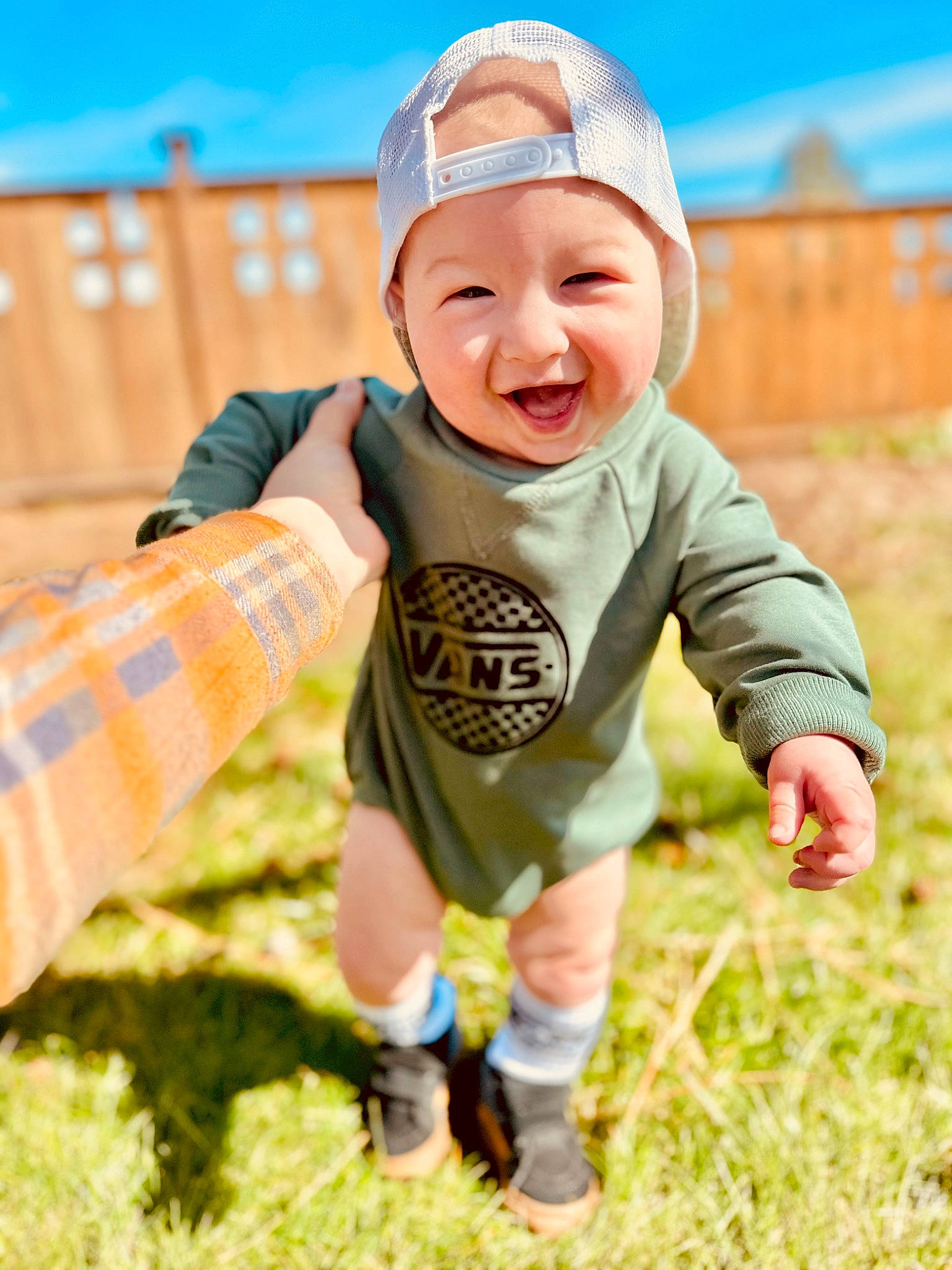 Kane is registered to the contest to win money with this photo: baby, baby_toddler_clothing, cap, child, finger, fun, grass, grassland, happy, hat, headwear, landscape, leisure, pattern, people_in_nature, person, recreation, sitting, sky, sleeve