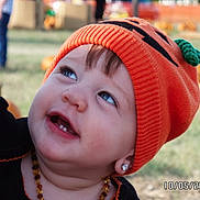 Leiha Andrade joined the competition — help win amazing prizes! toddler, child, orange_hat, pumpkin_hat, earrings, smiling, outdoor, grass, pumpkins, autumn, cute, portrait, knit_hat, baby, face, happy, jewelry, seasonal, festival, playful