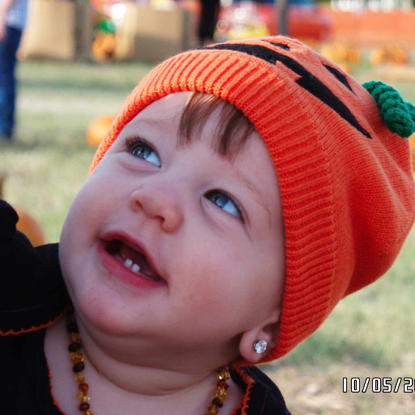 Leiha Andrade joined the competition — help win amazing prizes! toddler, child, orange_hat, pumpkin_hat, earrings, smiling, outdoor, grass, pumpkins, autumn, cute, portrait, knit_hat, baby, face, happy, jewelry, seasonal, festival, playful