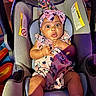 baby, car_seat, party_hat, headband, surprised_expression, infant, clothing, socks, indoor, colorful, child, cute, seat, fabric, person, celebration, portrait, mickey_mouse, pink, fun