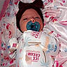 baby, pacifier, headband, onesie, blanket, infant, sleepy, patterned_clothing, pink, white, lying_down, face, cute, soft_texture, cozy, child, small, newborn, indoors, wearing