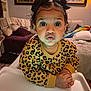 child, toddler, baby, highchair, leopard_print, sweater, hair_bows, wide_eyes, surprised_expression, hands, earrings, indoor, living_room, couch, blanket, painting, lamp, toy, portrait, closeup