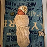 Kyaire is registered to the contest to win money with this photo: newborn, baby, swaddle, hat, sleeping, blanket, pacifier, bottle, crib, infant, bed, resting, cute, cozy, child, sleep, soft, pattern, text, nursery