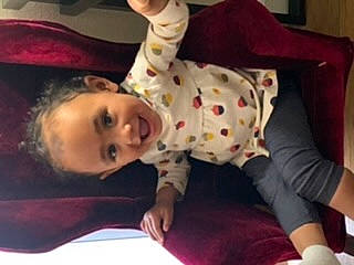 Carmen is registered to the contest to win money with this photo: baby, baby_toddler_clothing, cheek, child, comfort, eyelash, finger, flooring, fun, happy, joy, nightwear, nose, pattern, person, room, sitting, sleeve, smile, toddler