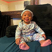 Ocean joined the competition — help win amazing prizes! baby, child, infant, smiling, happy, portrait, sitting, bed, cushion, pajamas, headband, indoor, bedroom, mirror, red_lights, home, barefoot, tongue_out, furniture, photography
