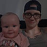 Skarlett joined the competition — help win amazing prizes! baby, child, adult, tattoos, glasses, cap, smile, indoor, person, portrait, holding, pink_shirt, face, head, seated, couch, casual, young_adult, happy, family