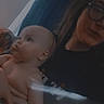 baby, person, indoor, curtain, glasses, shirt, holding, portrait, child, face, diaper, furniture, wall, picture_frame, window, dark, blur, smile, hair, skin