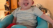 Vivian joined the competition — help win amazing prizes! baby, smiling, tongue_out, sitting, baby_seat, gray_shirt, red_pants, indoor, furniture, cabinet, baby_bottle, happy, cute, child, person, home, table, foot, head, room