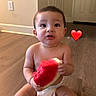 baby, child, watermelon, fruit, eating, sitting, indoor, wood_floor, home, face, smiling, infant, diaper, barefoot, portrait, heart, emoji, kitchen, door, outlet