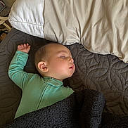 Adriel is registered to the contest to win money with this photo: baby, sleeping, onesie, blanket, pillow, bed, quilt, face, child, indoor, rest, peaceful, cozy, soft, toddler, young_child, person, comfort, nap, quiet