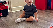 Adriel joined the competition — help win amazing prizes! baby, child, toddler, sitting, indoors, portrait, face, wide_eyed, surprised, dark_clothing, socks, wood_floor, window, blinds, toolbox, storage_cube, punching_bag, playroom, home, photography