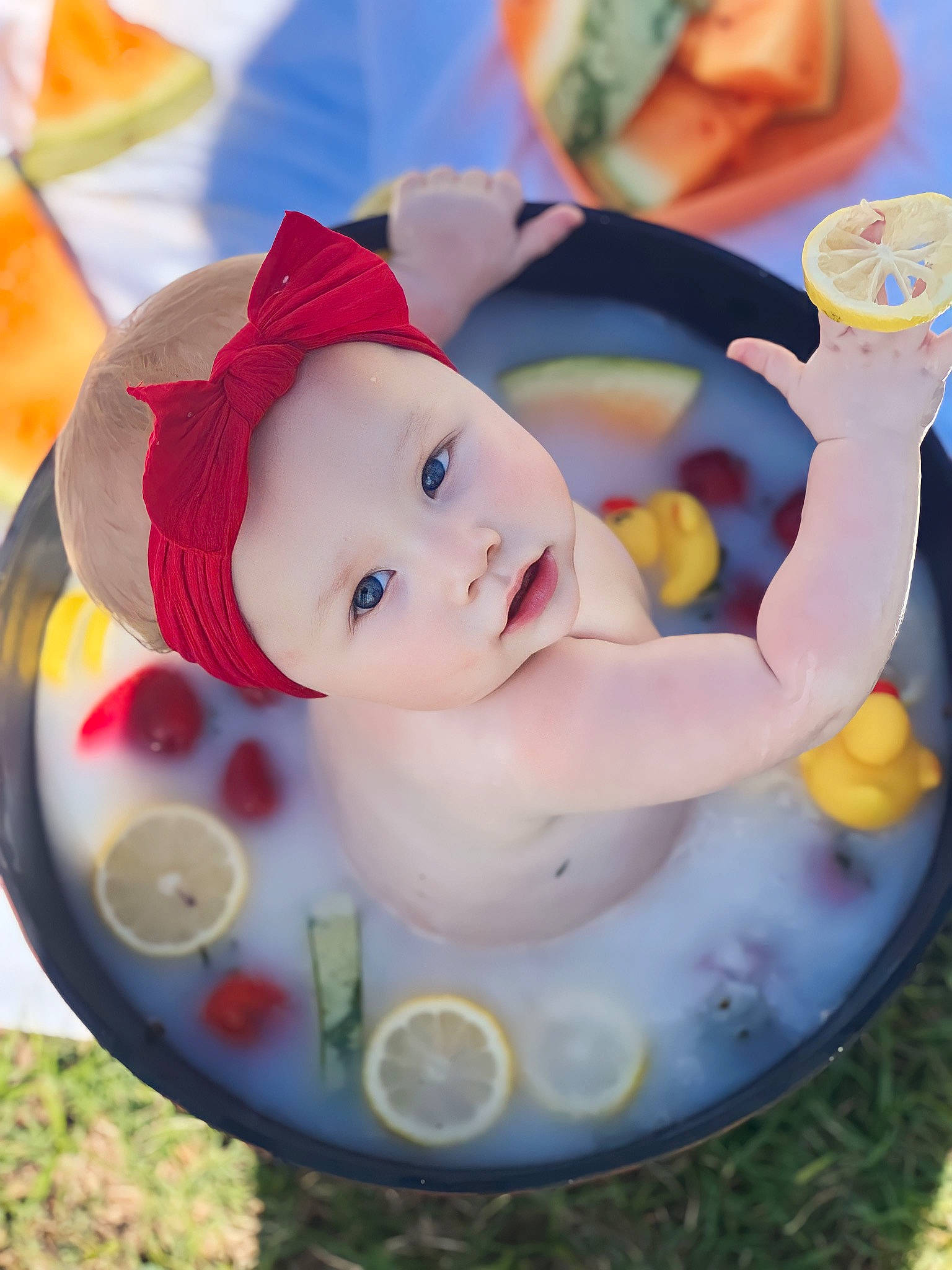 Adilynn is registered to the contest to win money with this photo: baby, baby_products, bathing, cap, cheek, child, drinkware, event, facial_expression, fictional_character, fun, grass, happy, hat, headwear, leisure, person, play, recreation, sweetness
