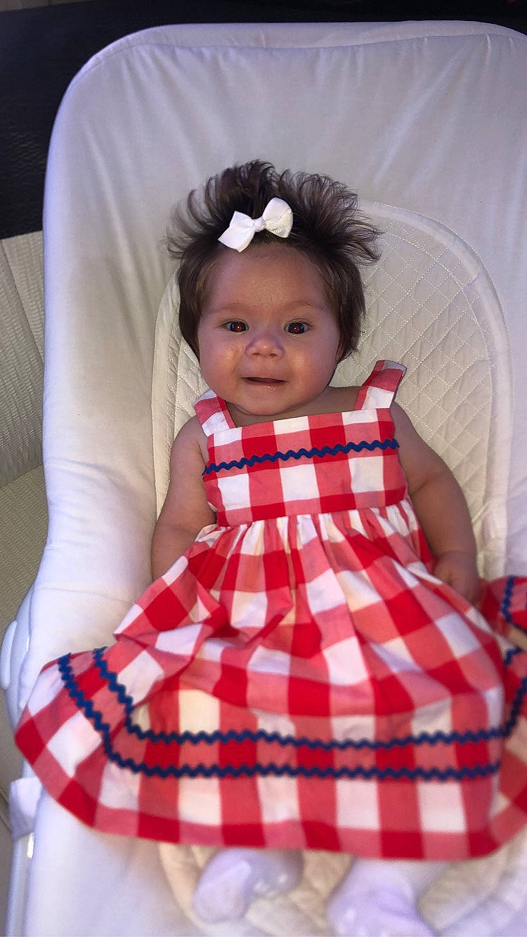 Ali participe au concours pour gagner de l'argent avec cette photo : arm, baby_toddler_clothing, chin, day_dress, dress, eyelash, face, head, lip, neck, one_piece_garment, person, pink, plaid, skin, sleeve, smile, tartan, toddler, waist