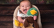 Brayden joined the competition — help win amazing prizes! baby, background, child, colorful, comfort, cute_outfit, duck, fabric, happy, indoor, infant, laughing, playful, plush_toy, portrait, sitting, smiling, soft_chair, toy, wooden_floor
