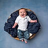 baby, infant, smiling, white_polo_shirt, denim_jeans, basket, blue_blanket, studio_background, happy, cute, portrait, clothing, child, sitting, feet, hands, head, face, casual_wear, indoor