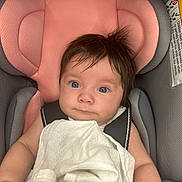 Meara is registered to the contest to win money with this photo: baby, car_seat, blanket, bracelet, child, infant, face, hair, person, seat_belt, pink, gray, white, clothing, indoors, cute, portrait, looking_at_camera, young_child, toddler
