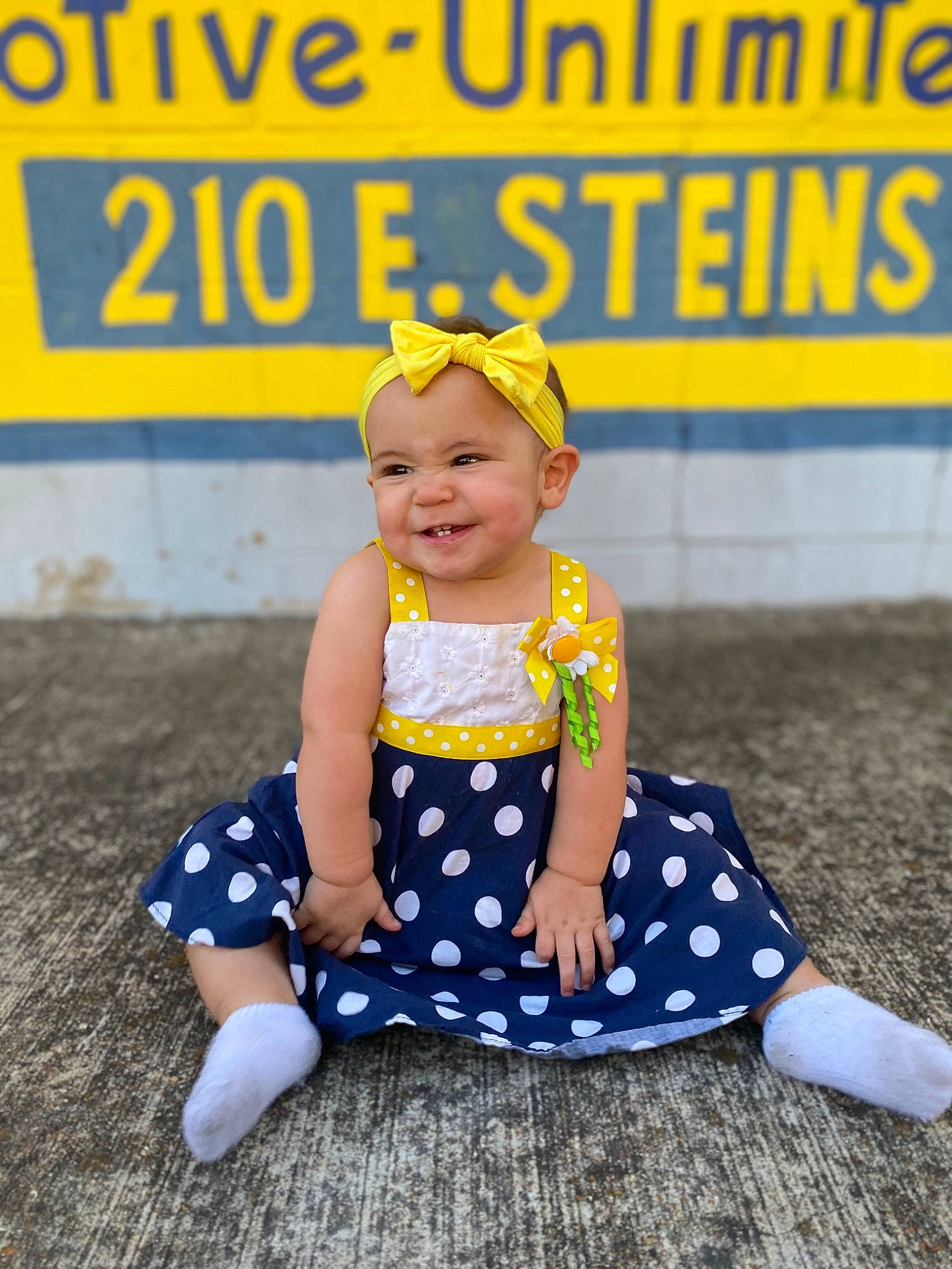 Lorelai is registered to the contest to win money with this photo: baby_toddler_clothing, child, dress, electric_blue, face, fun, happy, headgear, headwear, joy, leisure, logo, pattern, performing_arts, person, polka_dot, portrait_photography, recreation, sitting, sleeve