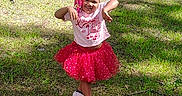 Anaya joined the competition — help win amazing prizes! child, girl, smiling, dancing, outdoor, park, trees, grass, sunlight, pink_clothing, skirt, t_shirt, sneakers, braids, playful, portrait, full_body, summer, nature, playground