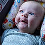 baby, infant, face, smile, blue_eyes, cushion, floral_pattern, clothing, close_up, portrait, child, cute, happy, indoor, soft_lighting, newborn, skin, head, expression, comfort
