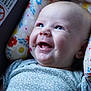 Willow is registered to the contest to win money with this photo: baby, infant, smiling, face, blue_eyes, clothing, floral_pattern, cushion, colorful, closeup, portrait, happy, cheeks, dimple, head, seat, fabric, indoors, expression, child