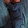 baby, sleeping, blue_outfit, knitted_clothing, hat, bed, sheet, arrow_pattern, infant, peaceful, resting, cozy, newborn, child, portrait, cute, indoor, soft_lighting, hands_together, footed_pajamas