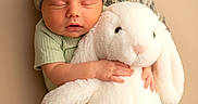 Colt joined the competition — help win amazing prizes! baby, newborn, sleeping, plush_toy, bunny, cuddle, knit_cap, soft_texture, green_clothing, infant, child, cute, peaceful, portrait, indoors, warm_colors, cozy, hands, face, toddler