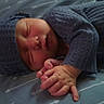 newborn, baby, sleeping, blue_clothing, knitted_hat, knitted_outfit, infant, hands, closed_eyes, blanket, pattern, arrows, soft_lighting, cozy, portrait, resting, cute, peaceful, young_child, indoor