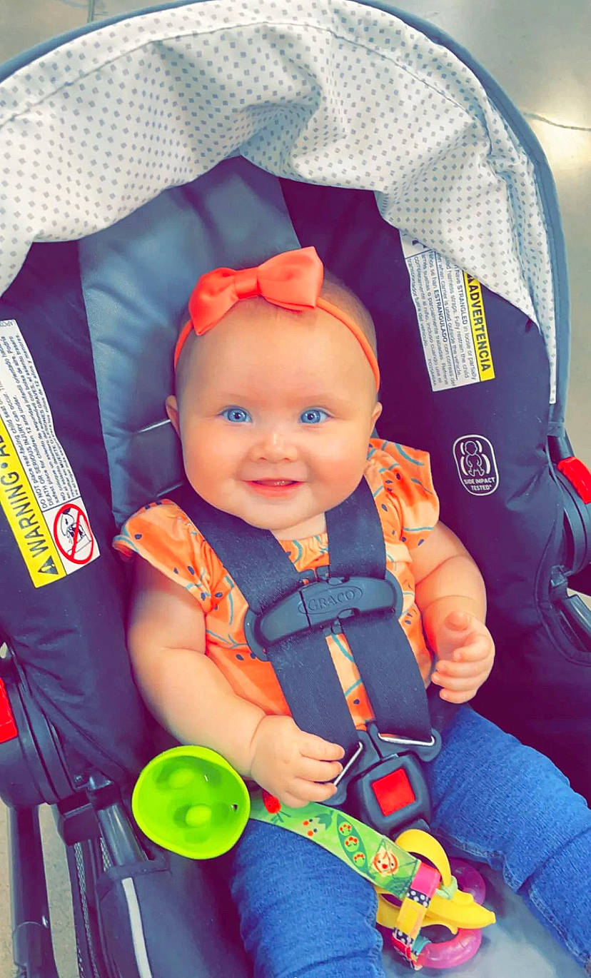 Kallie is registered to the contest to win money with this photo: baby, baby_carriage, baby_products, baby_safety, baby_toddler_clothing, child, comfort, cool, electric_blue, fun, happy, headwear, joy, orange, person, personal_protective_equipment, product, purple, sitting, smile