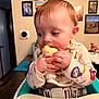 baby, child, toddler, highchair, eating, apple, bib, hands, face, closeup, indoor, kitchen, mealtime, seatbelt, portrait, photography, shelf, picture_frames, cute, snack