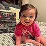 Adrianna is registered to the contest to win money with this photo: baby, child, crawling, pink_shirt, bed, striped_bedding, daycare_board, indoor, cute, smiling, face, hair, skin, pillow, toy, milestone, celebration, happy, infant, portrait