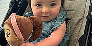 Adrianna is registered to the contest to win money with this photo: toddler, child, stroller, plush_doll, toy, blue_flower, hair_clip, smile, curious, indoor, cute, baby, denim_dress, pink_pants, soft_toy, portrait, infant, hand, face, young_child