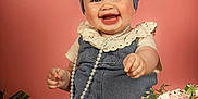 Romy a rejoint le concours — aidez-le/la à gagner de superbes lots ! baby, child, smile, denim, headband, pearl_necklace, flowers, pink_background, sitting, happy, cute, portrait, white_socks, floral_arrangement, infant, studio_photo, soft_lighting, decor, joyful, fashion