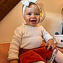 baby, smiling, headband, bow, white_clothing, corduroy_skirt, orange_skirt, tights, pacifier_clip, indoor, soft_lighting, wooden_beam, mirror, pink_surface, happy, child, portrait, cute, sitting, cozy
