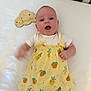 Cora is registered to the contest to win money with this photo: 3_months, baby, blue_eyes, child, clothing, crib, cute, dress, fruit_pattern, happy, head, indoors, infant, lying_down, skin, small_arm, smiling, white_mattress, wooden_sign, yellow_dress
