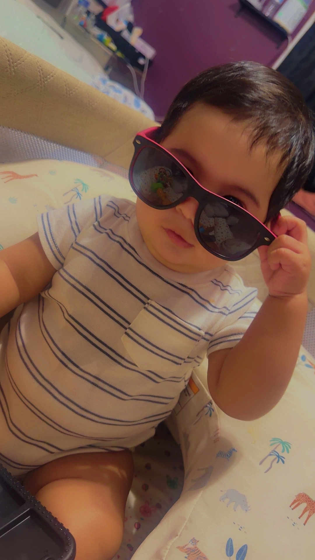 Endrick is registered to the contest to win money with this photo: baby, sunglasses, striped_shirt, infant, child, baby_seat, animal_print, indoor, portrait, cute, chubby, hand, face, person, clothing, furniture, cool, young_child, soft_lighting, casual